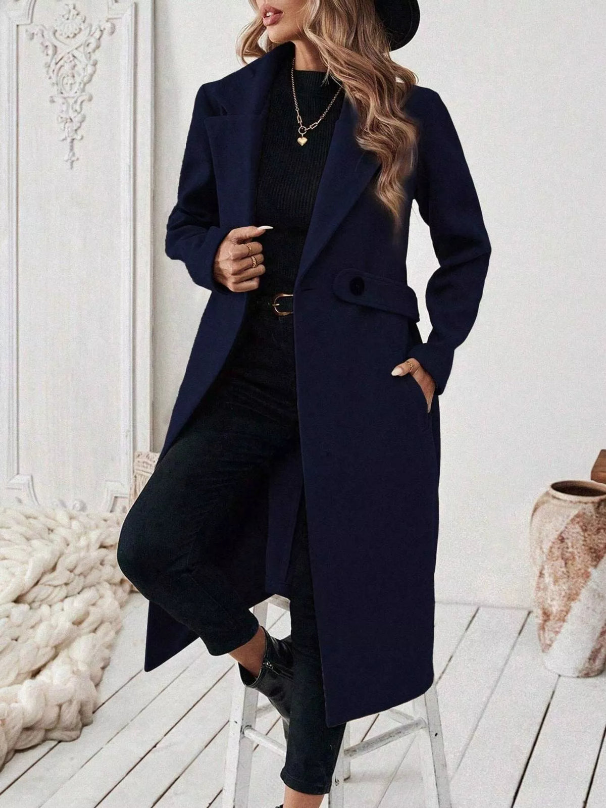 Navy longline coat with notched lapels, flap pockets, and button-front closure