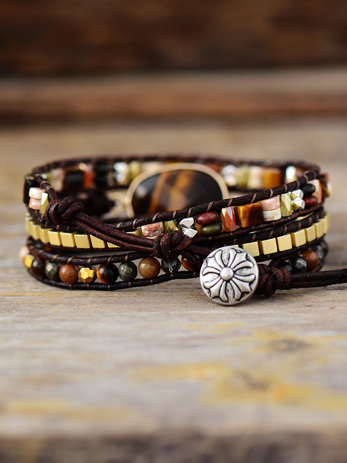 Triple-layer bracelet with oval wood face, braided cords, and silver flower charm