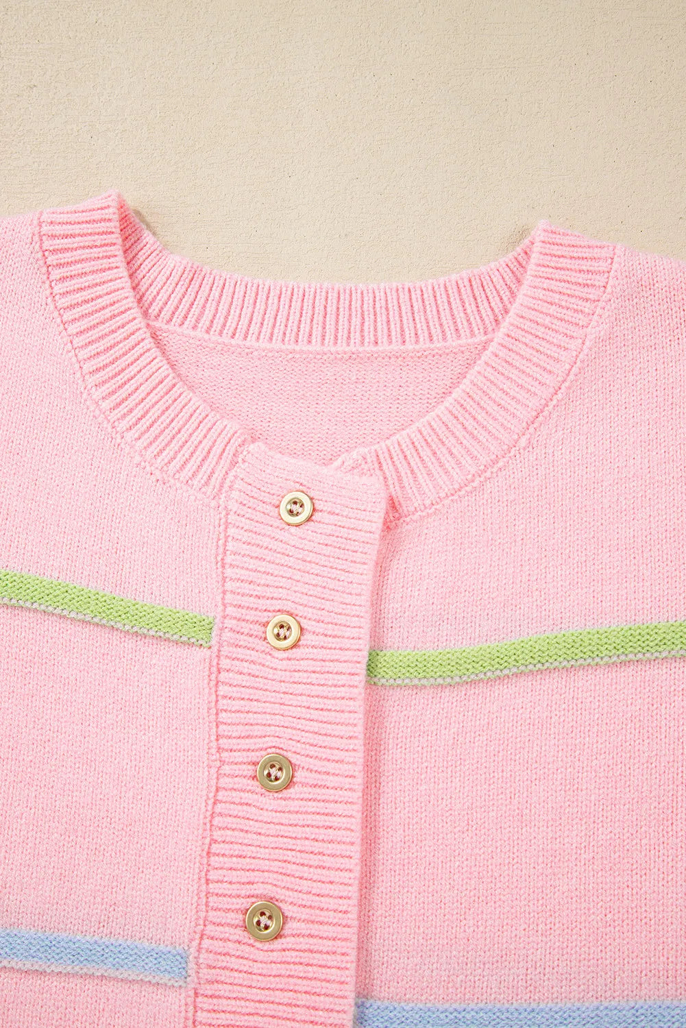 Blush pink sweater knit close-up: round neck, half-button placket with gold buttons and stripe bands
