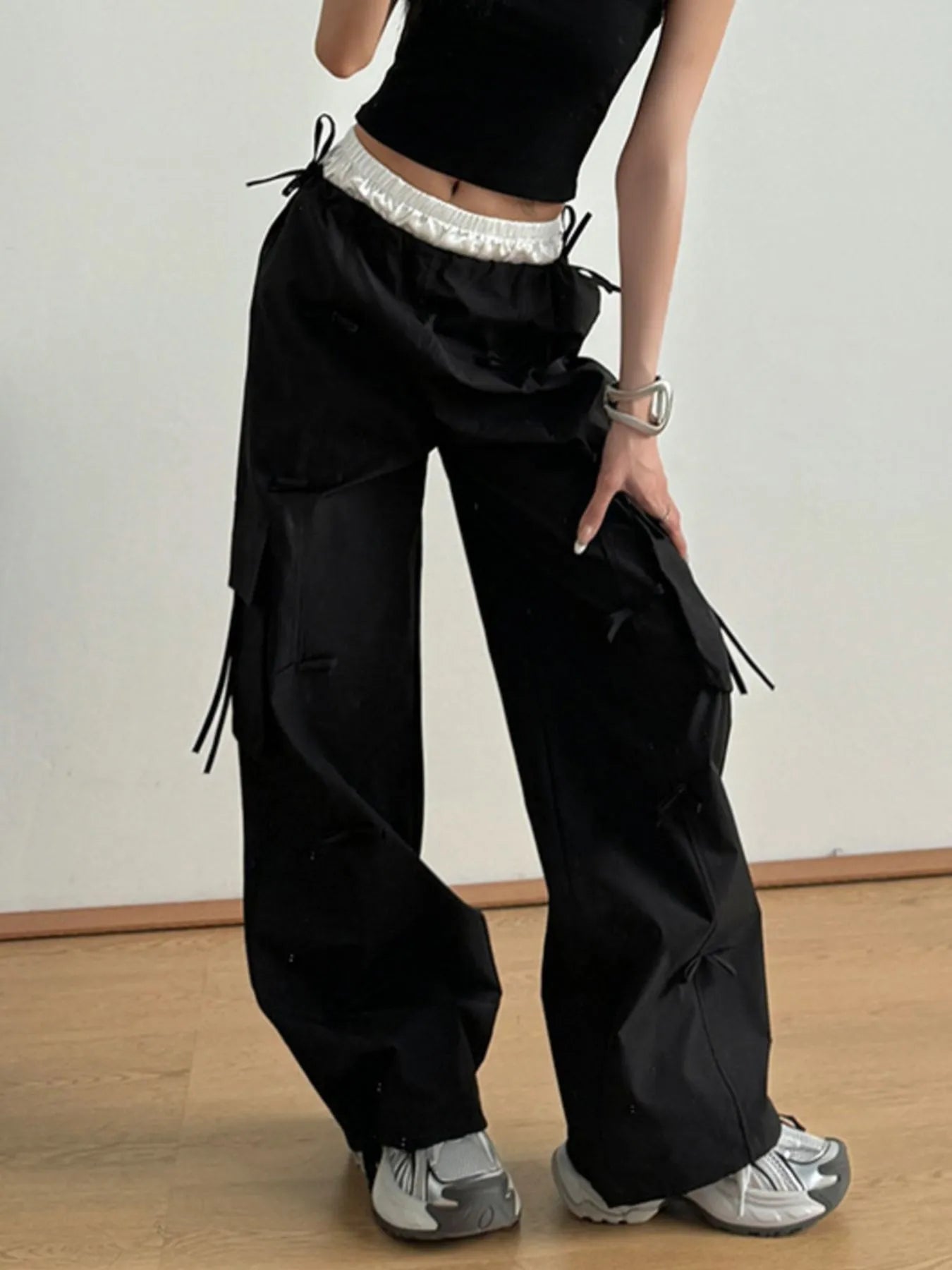 Black cargo pants with elastic waist, side bows, flap pockets, wide-leg fit