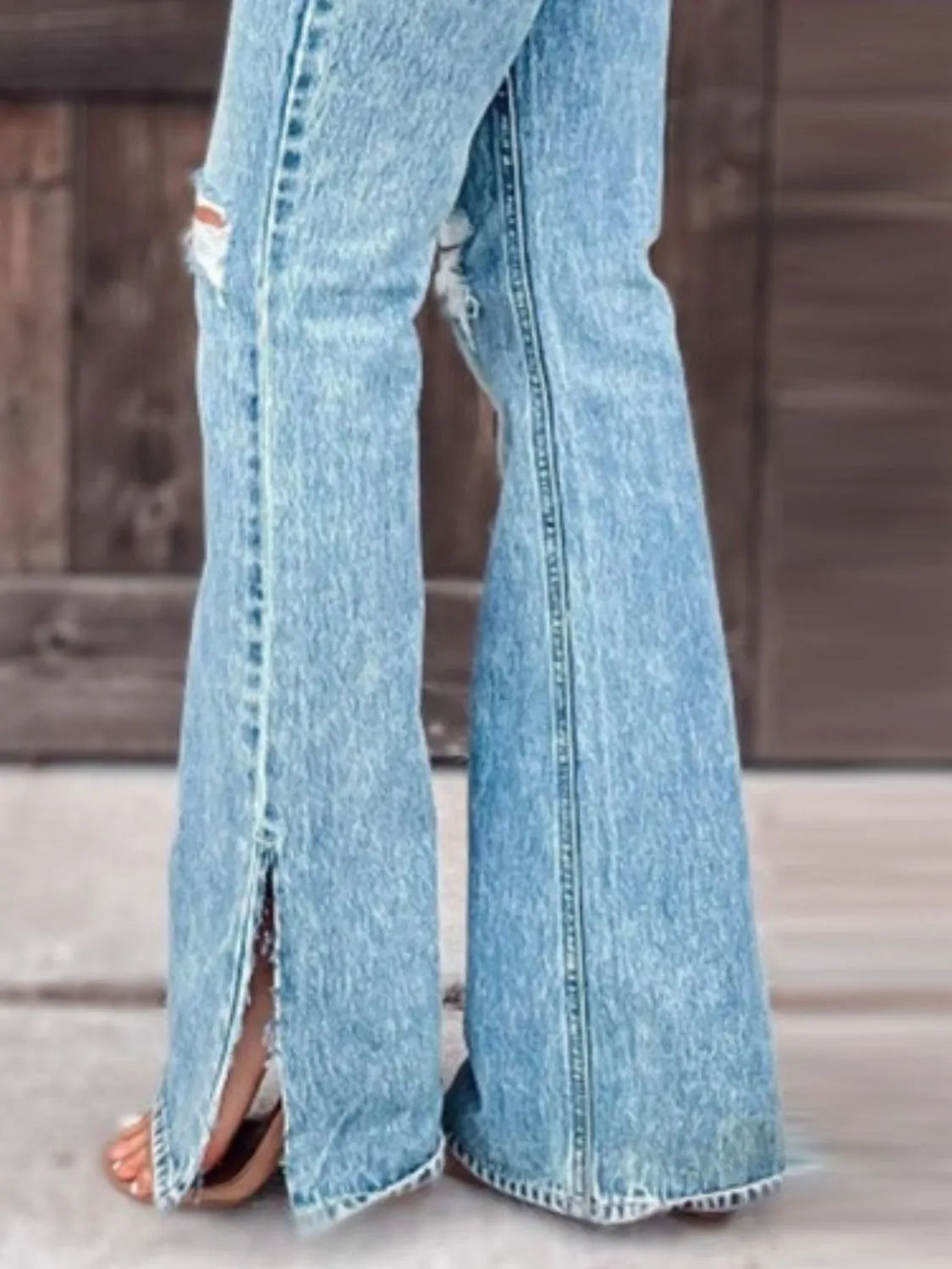 Light wash slit bootcut jeans with wide flare and distressed vertical leg rips