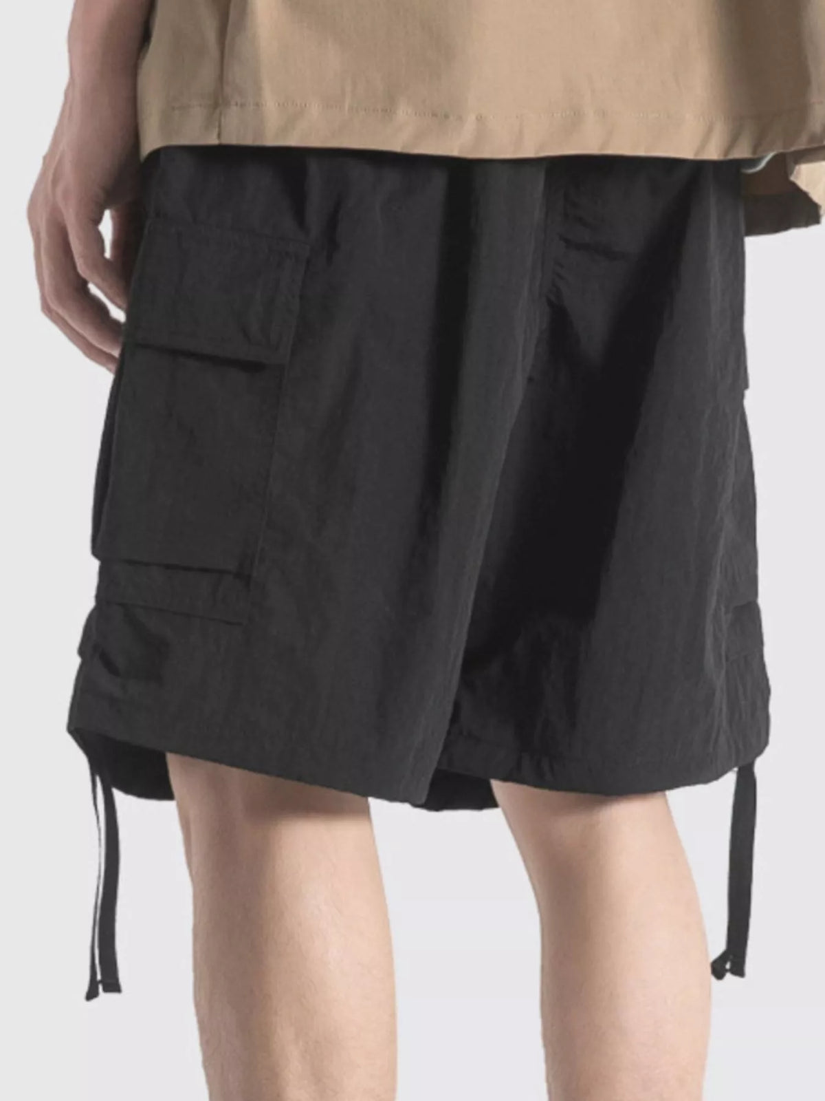 Black cargo shorts with flap pockets and long side drawstrings at hem