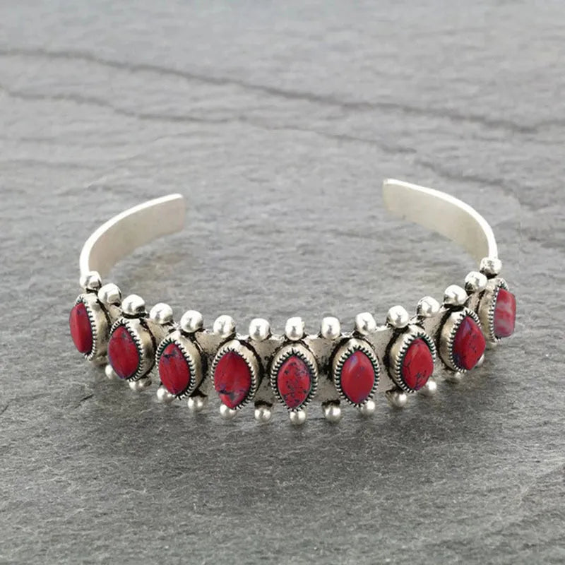 Open alloy bracelet with oval red stones, silver bead trim, and hinged cuff