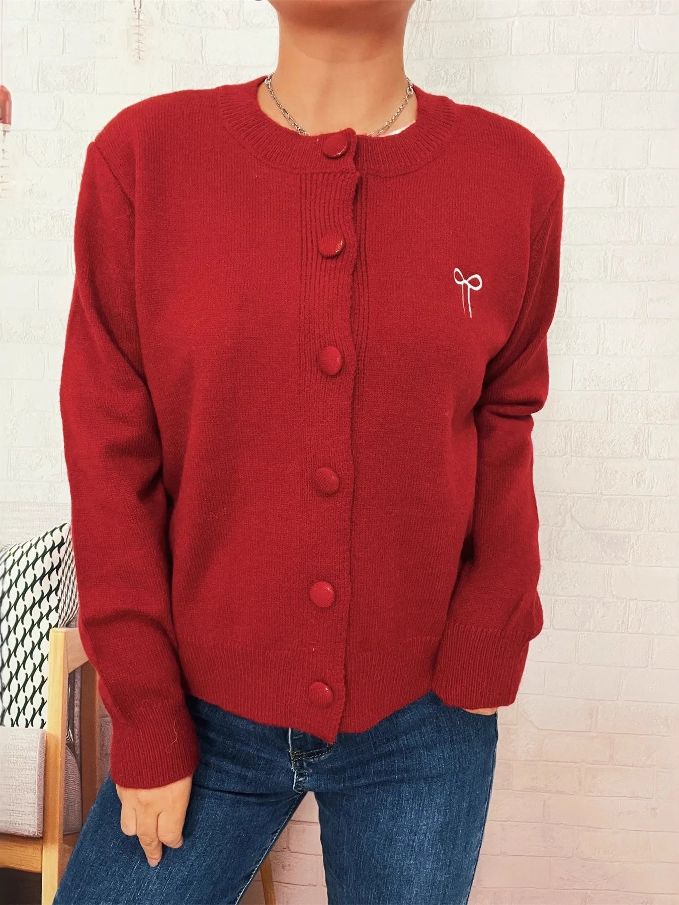 Red long-sleeve cardigan with button-front closure and bow embroidery on chest