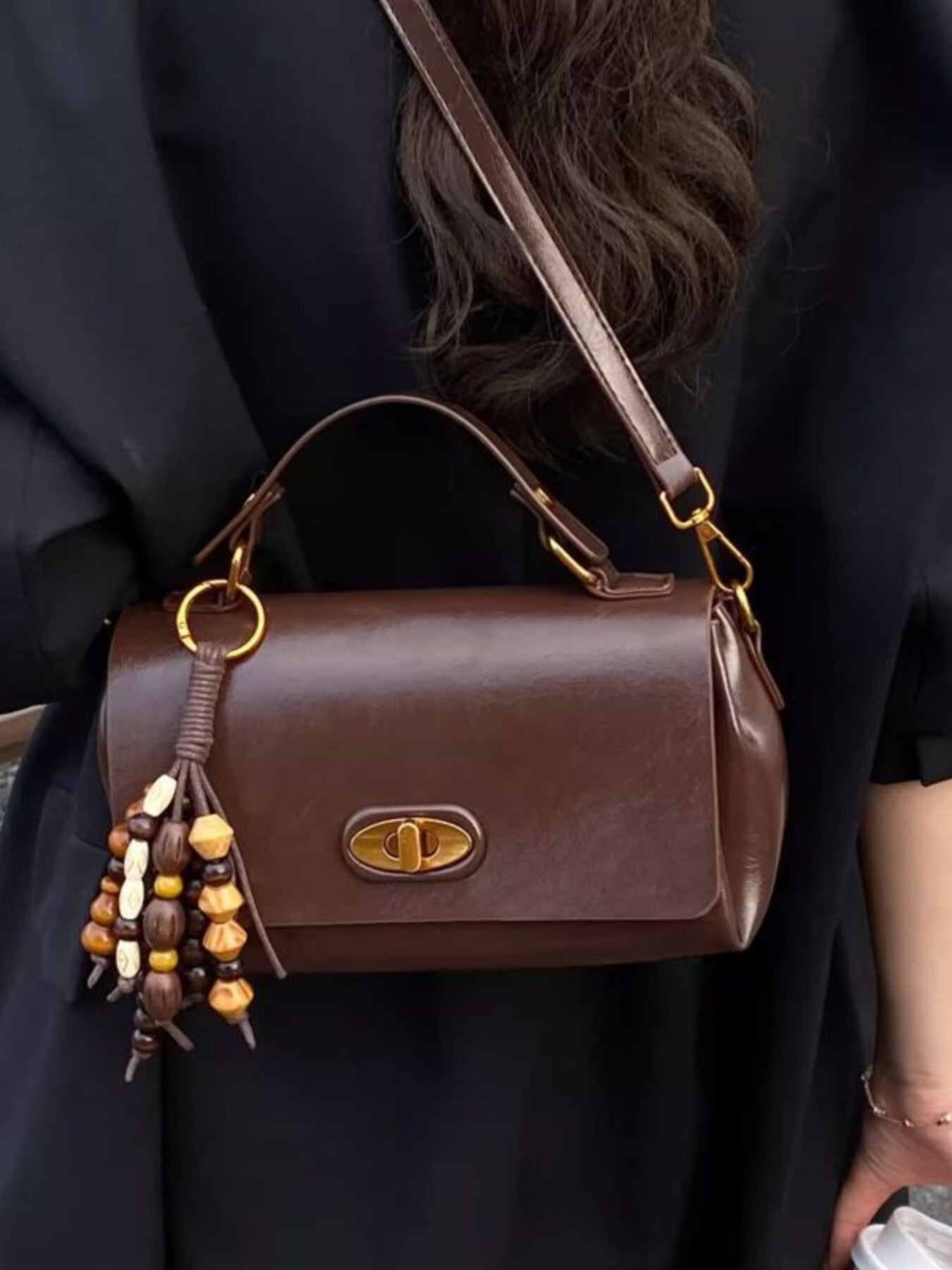 Small brown PU leather flap shoulder bag with gold-tone hardware, top handle and beaded tassel.