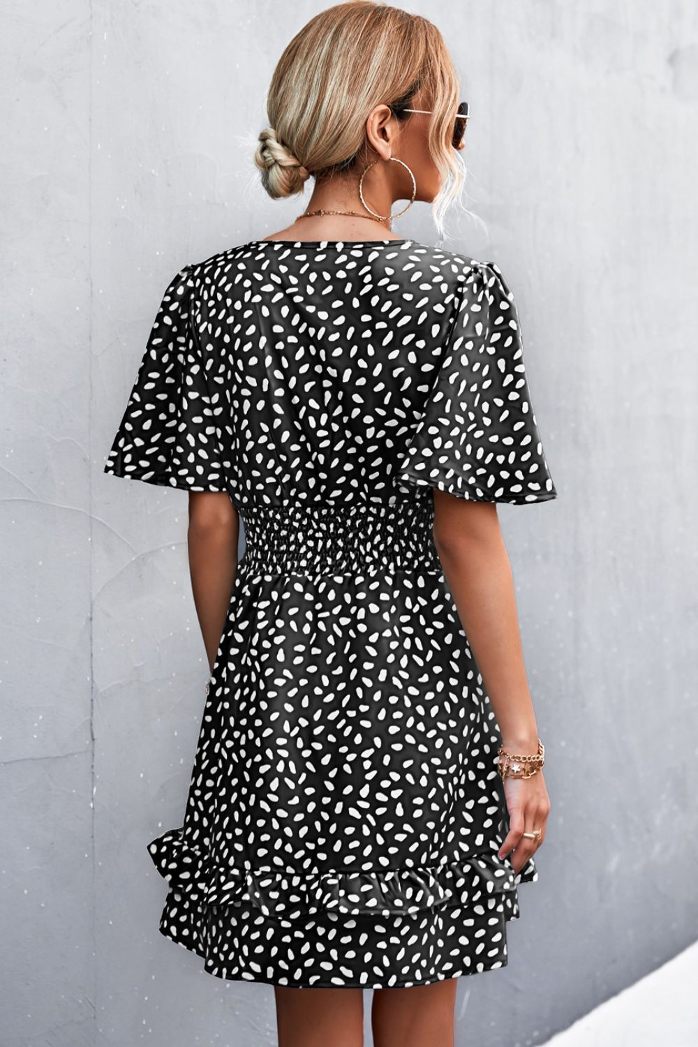 Black printed surplice mini dress with puff short sleeves and smocked waist, back view