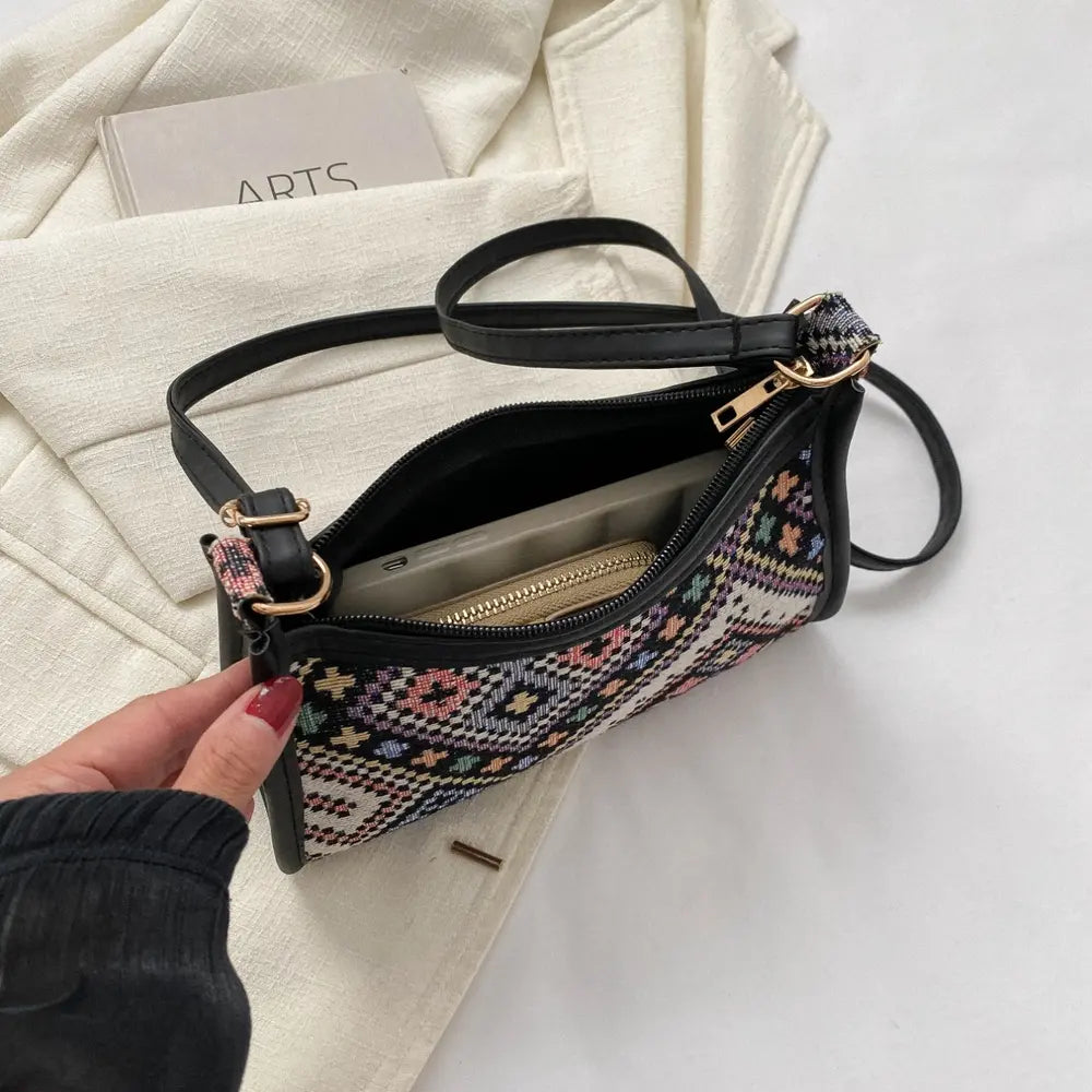 Crossbody bag exterior with black zipper and gold-tone pulls, shown open with lining