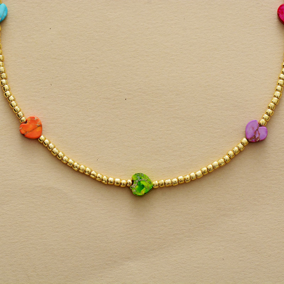 Gold-tone beaded necklace with a green center heart and purple, orange, and blue hearts