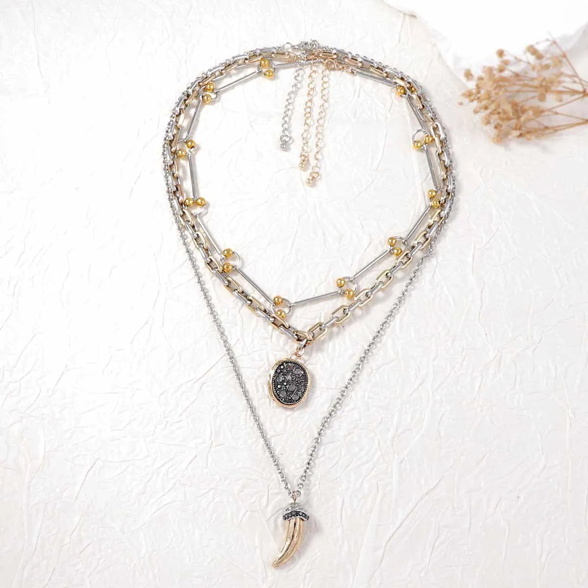 Layered pendant necklaces with mixed-tone chains, round dark medallion and horn charm