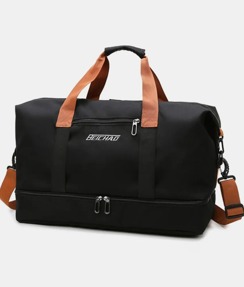 Black oversize travel duffle bag with tan handles, crossbody strap, and front zipper