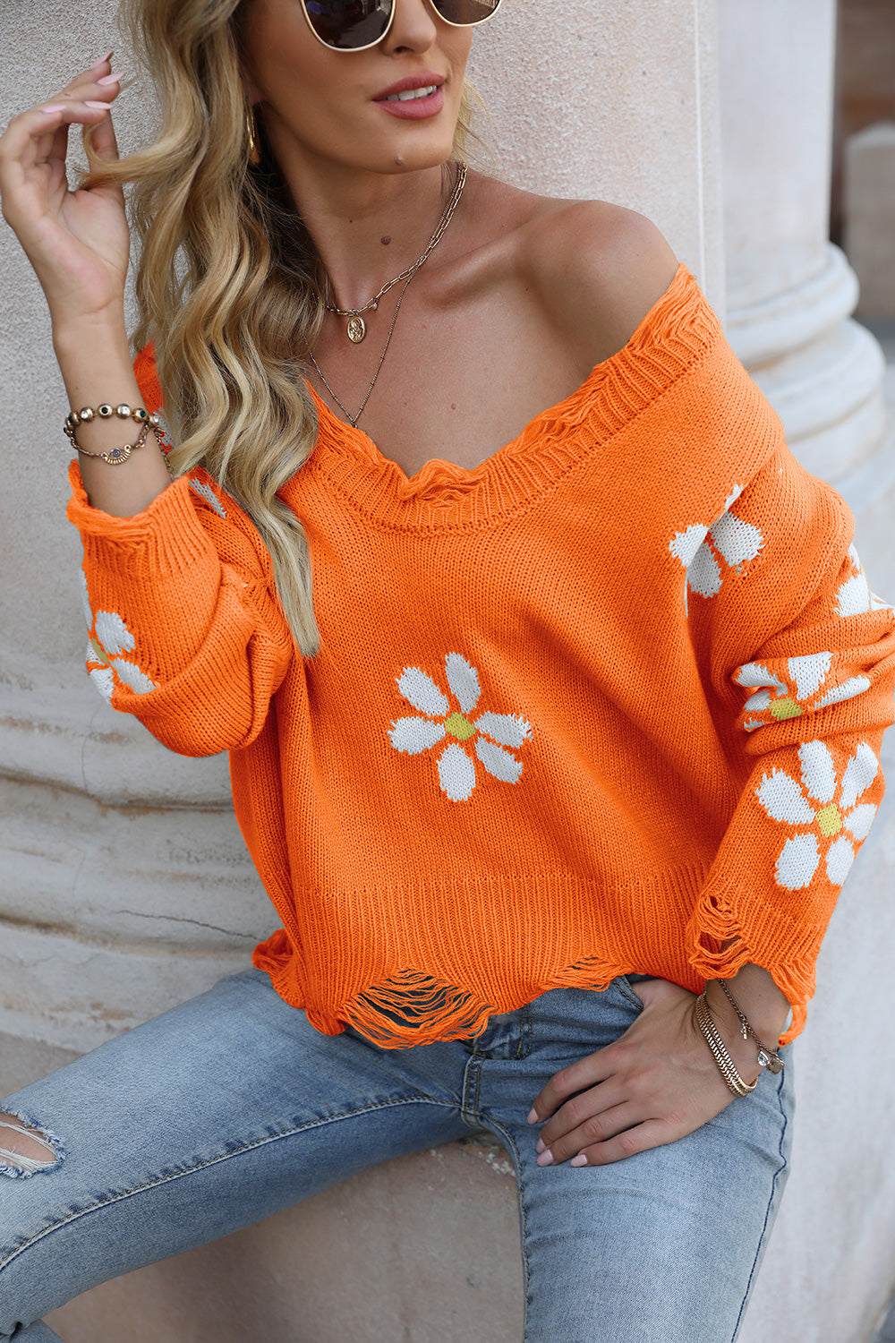 Orange V-neck sweater with white flower applique and frayed distressed bottom edge