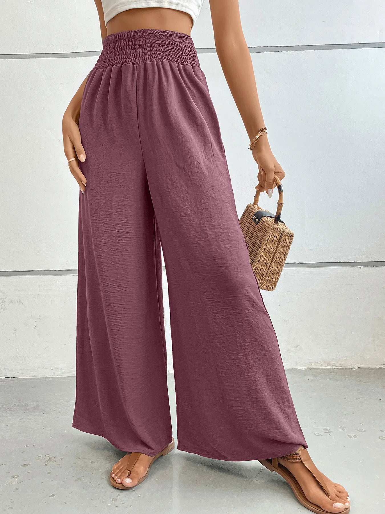 High-waisted wide-leg pants in mauve with elastic smocked waistband and flowing wide legs.