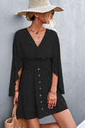 Black surplice dress with smocked waist, decorative buttons and flared sleeves