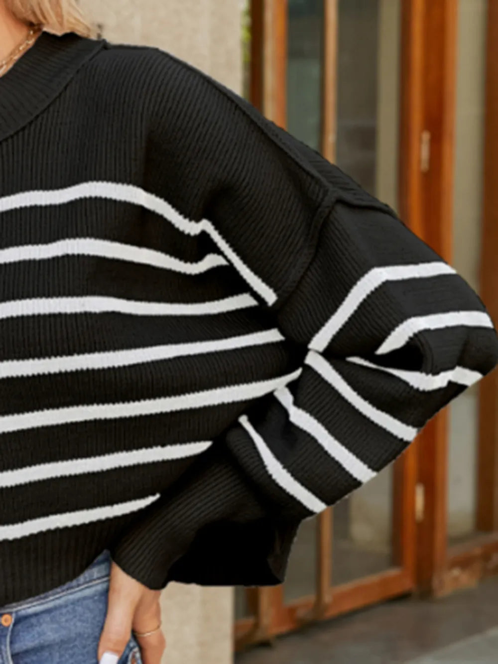 Black sweater sleeve with white horizontal stripes and ribbed knit cuff