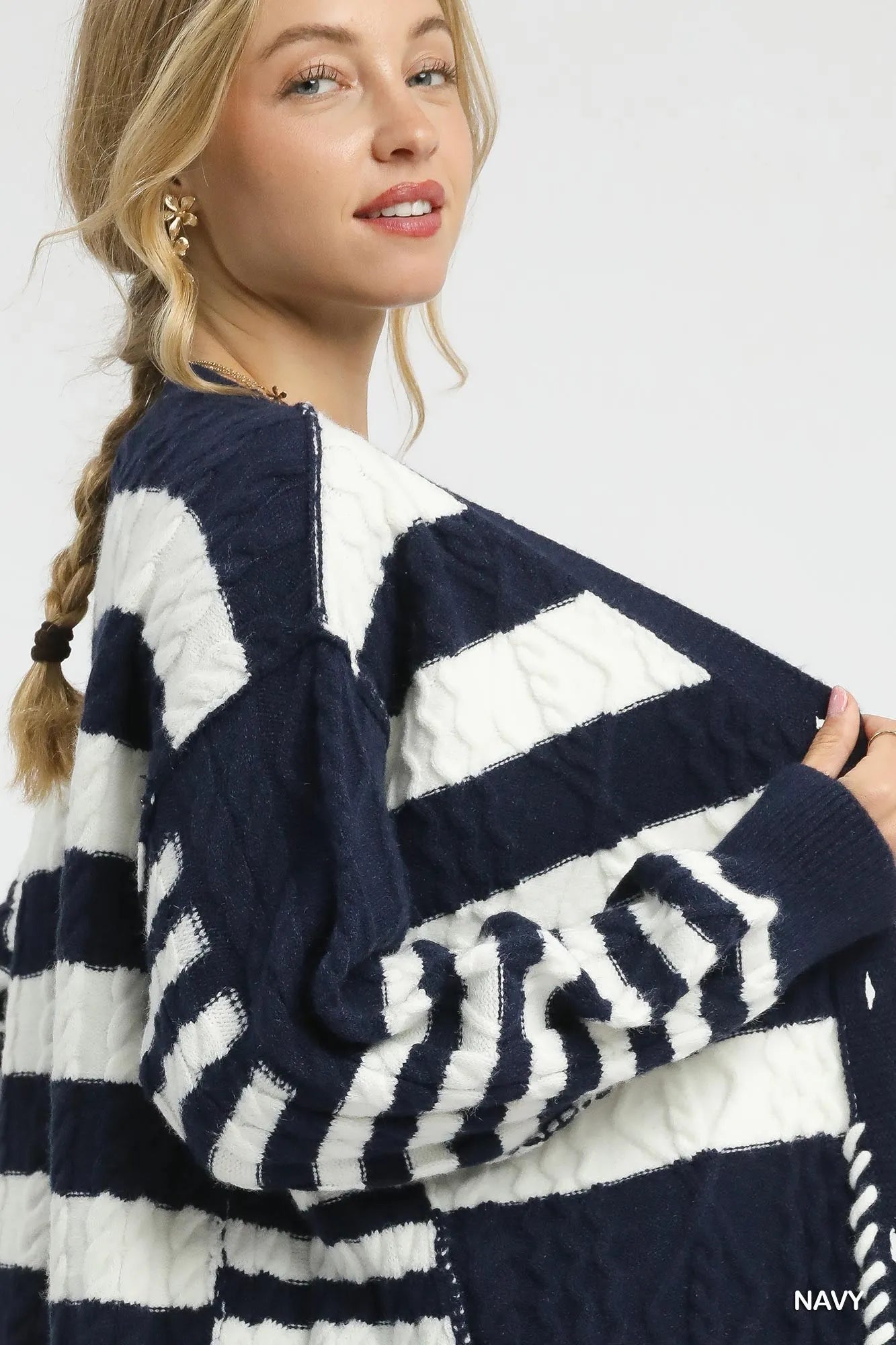 Navy cable-knit cardigan close-up with white stripes and button front detail
