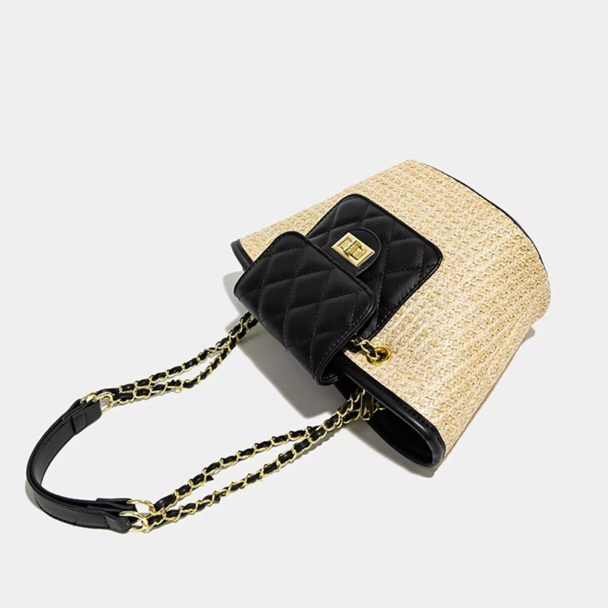 Woven straw shoulder bag with black quilted pocket, chain strap, and top handle