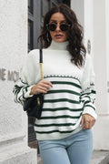 White knit turtleneck drop-shoulder sweater with dark green and black stripes at the hem