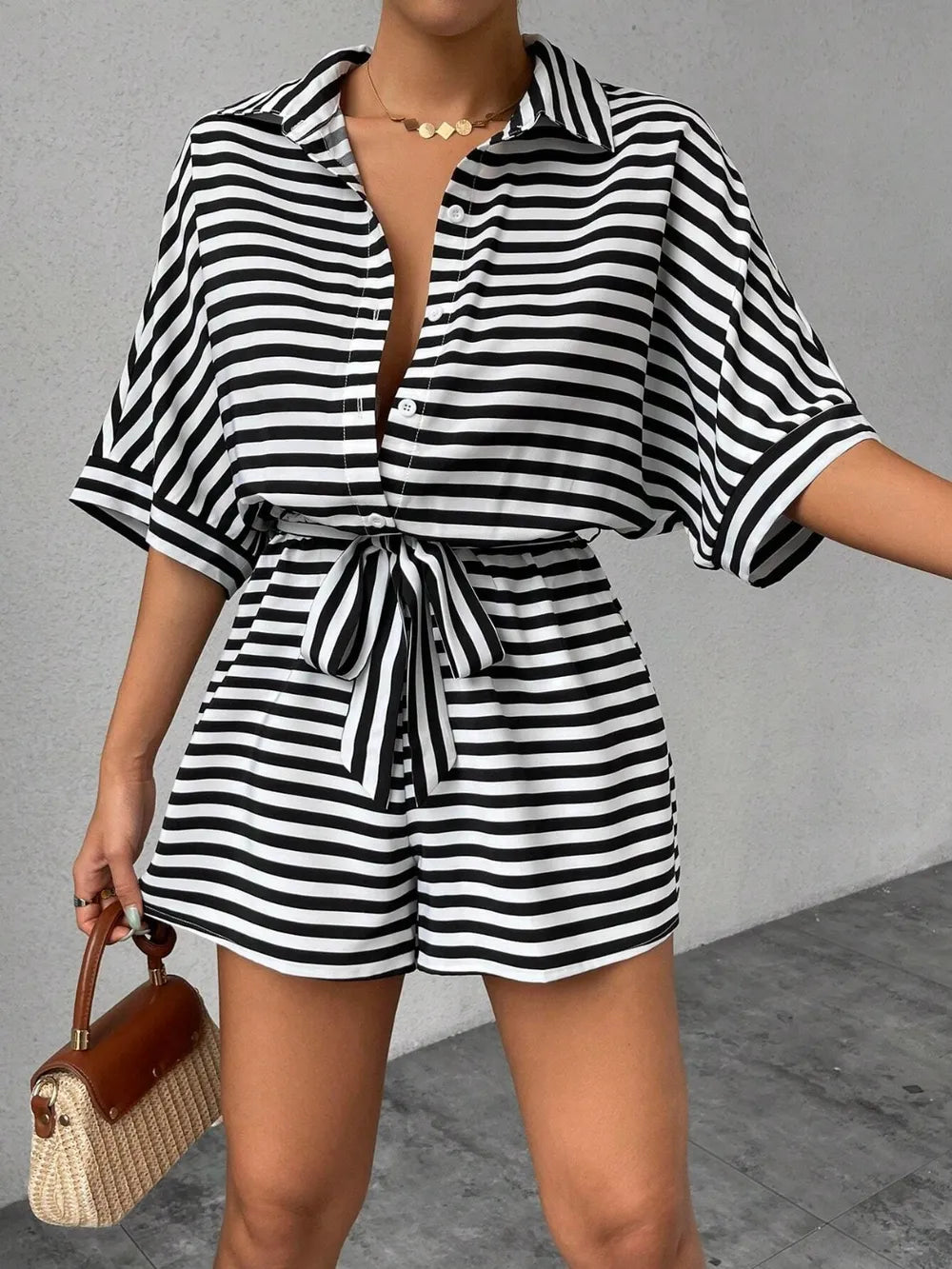Black and white striped button-front romper with tie waist and short sleeves
