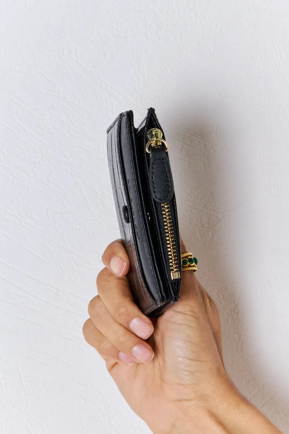 Black textured vegan leather mini wallet side view with gold-tone zipper and tab
