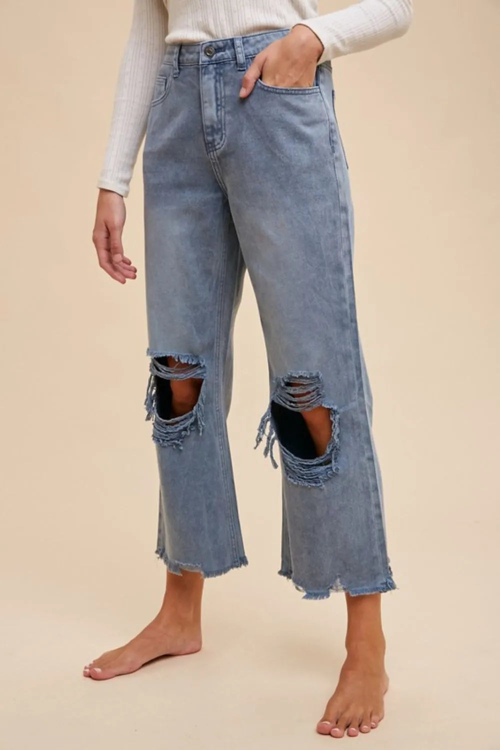 Dusty blue distressed raw-hem jeans with ripped knees and frayed cropped cuffs