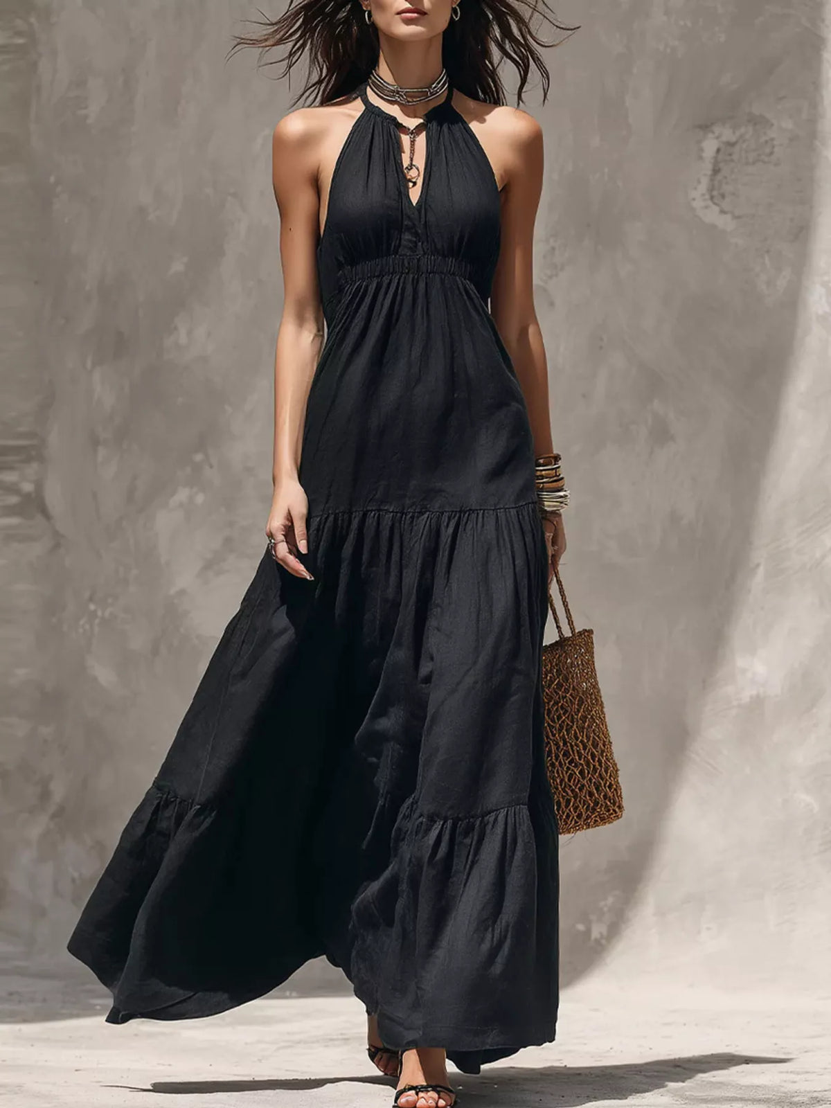 Black halter tiered maxi dress with gathered bodice and flowing layered skirt.