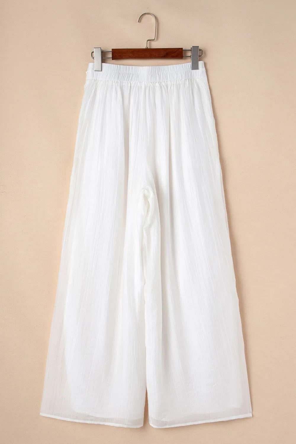 White tie-waist pleated wide-leg pants on hanger, loose fit and soft drape