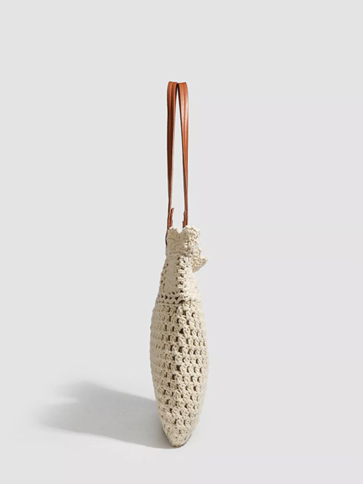 Cream crochet tote bag with brown leather shoulder handles and short stitched sides.