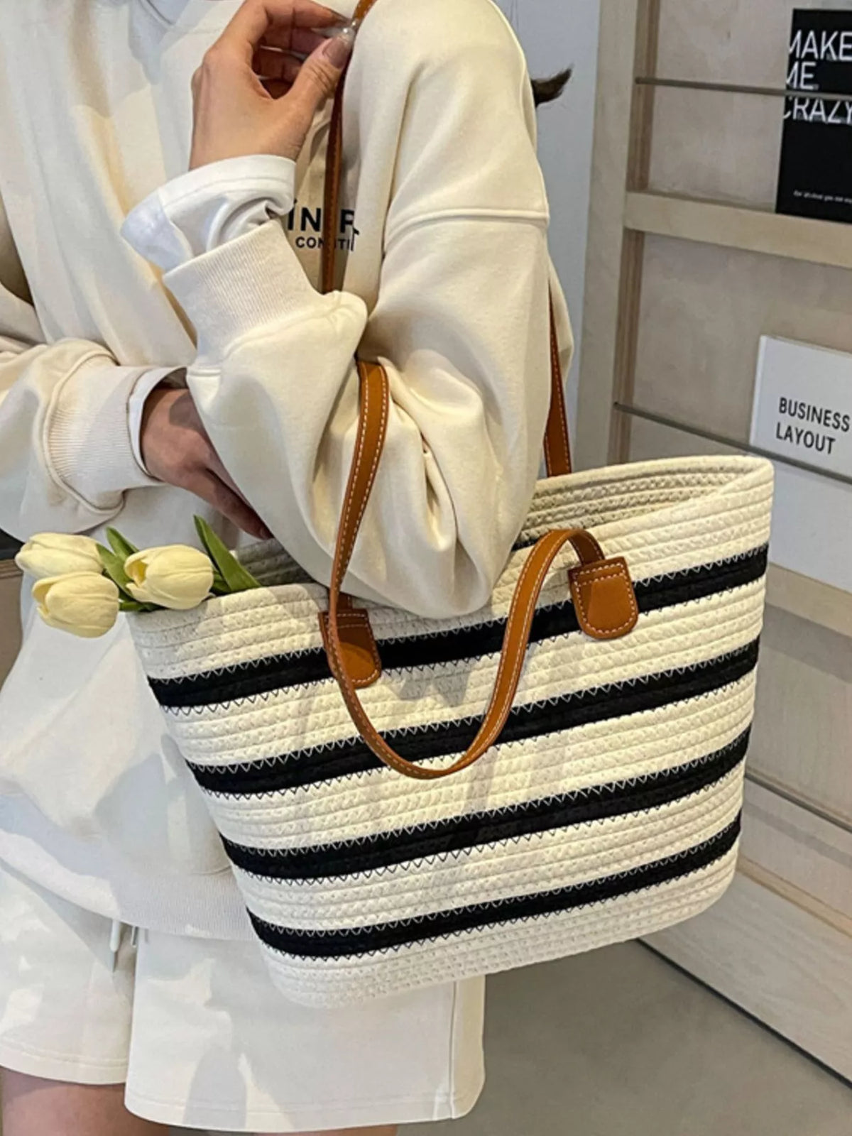 Striped straw tote bag with brown leather handles, white woven stripes with navy bands