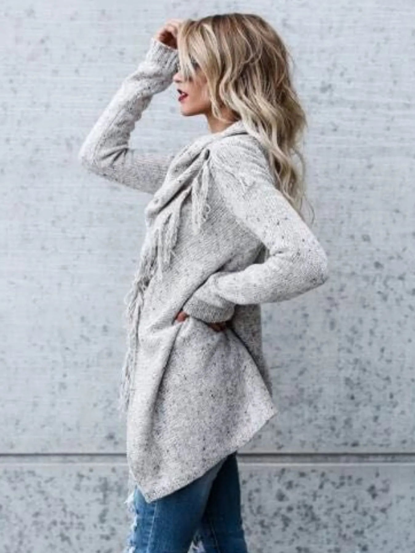 Light gray wrap cardigan with long sleeves, fringed cowl neck, and draped front