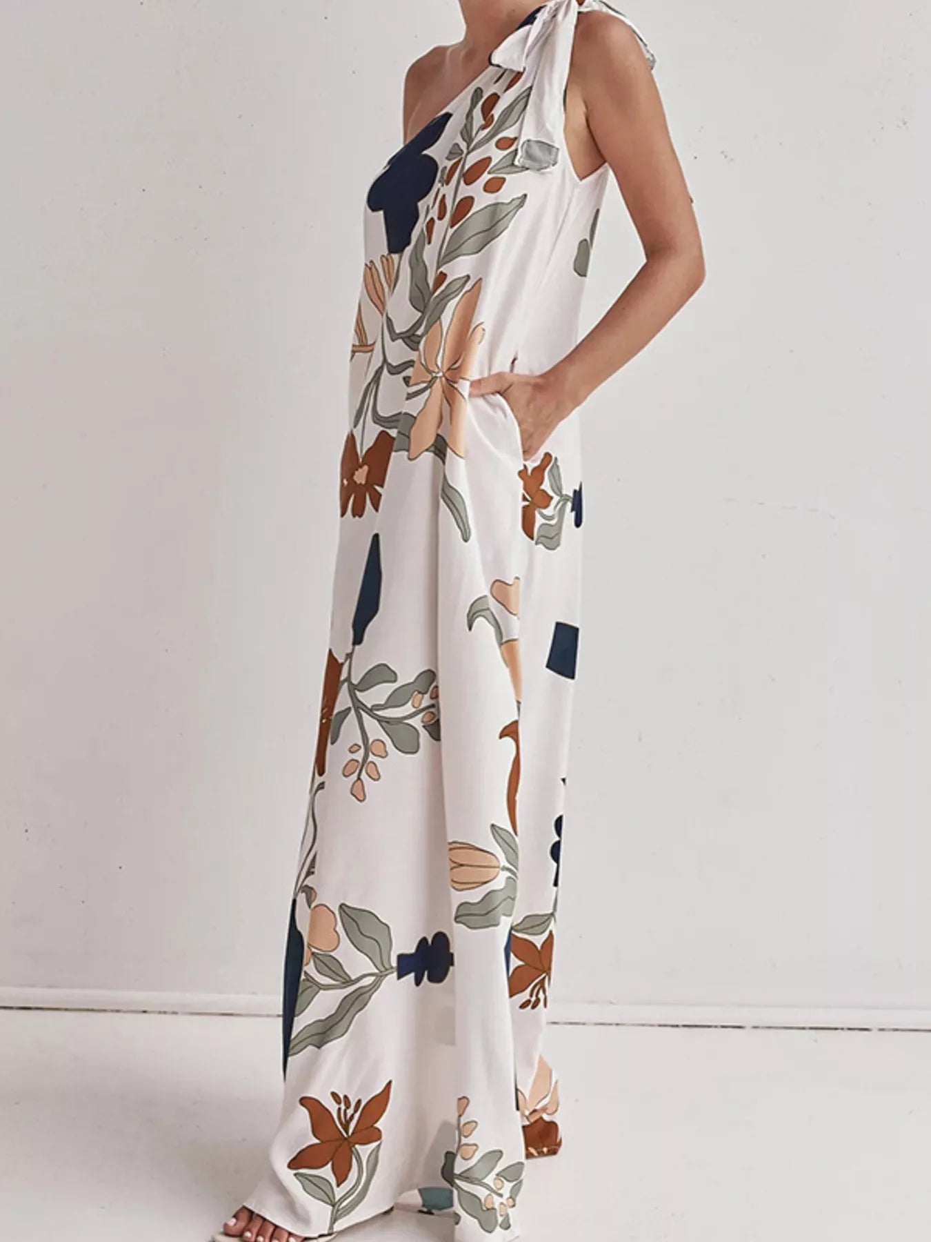 Cedar & Moore Bohemian Floral Print One-Shoulder Maxi Dress with pockets in white, orange/navy/sage blooms, tie strap.