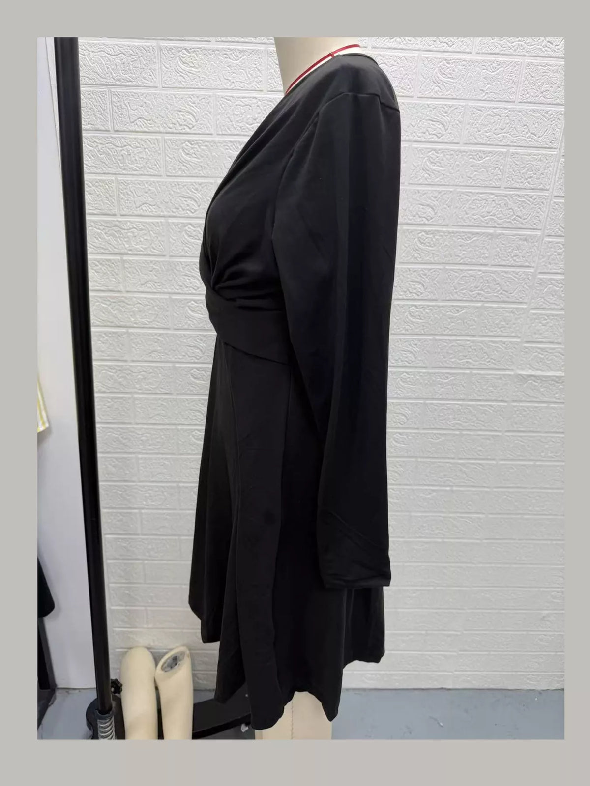 Black long-sleeve midi dress side view with ruched waist wrap and draped skirt
