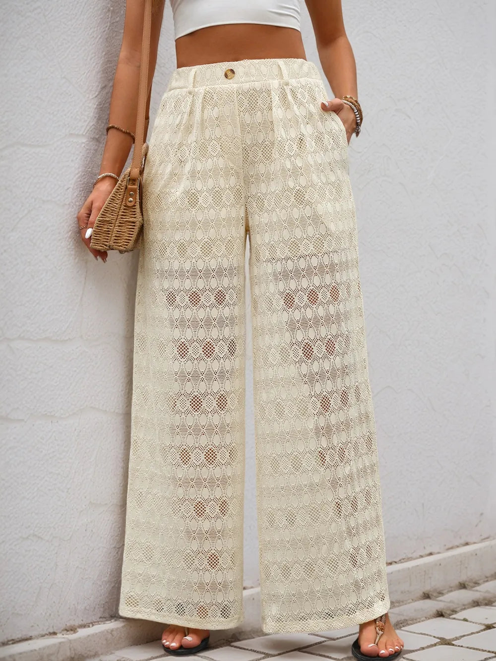 Cream wide-leg lace pants with decorative button closure and vertical geometric lace design