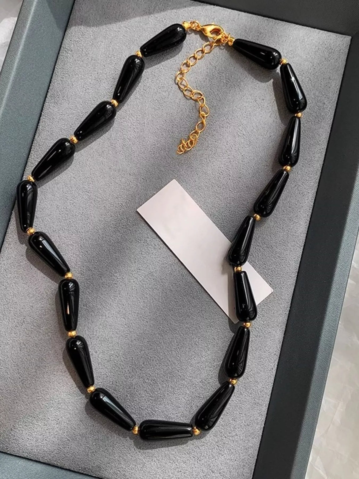 Black teardrop beaded necklace with gold-tone chain extender