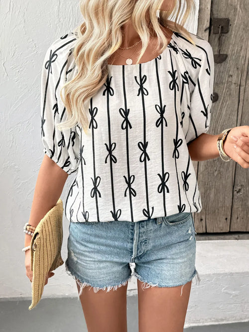 White blouse with black bow-pattern stripes and gathered puff sleeves, back view