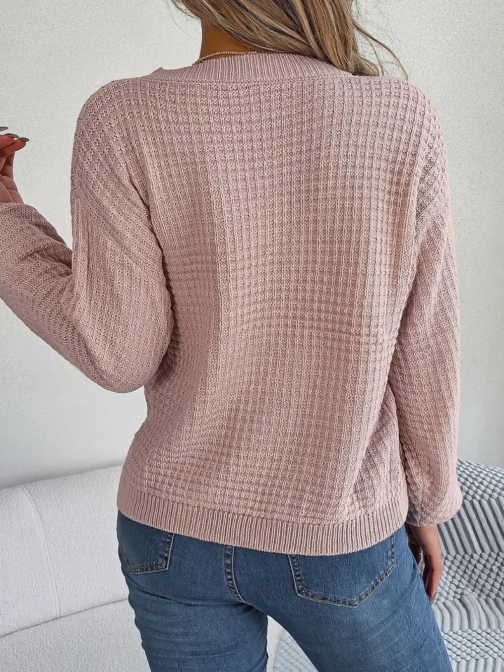 Blush cable-knit sweater back view with round neck and long sleeves; ribbed hem.