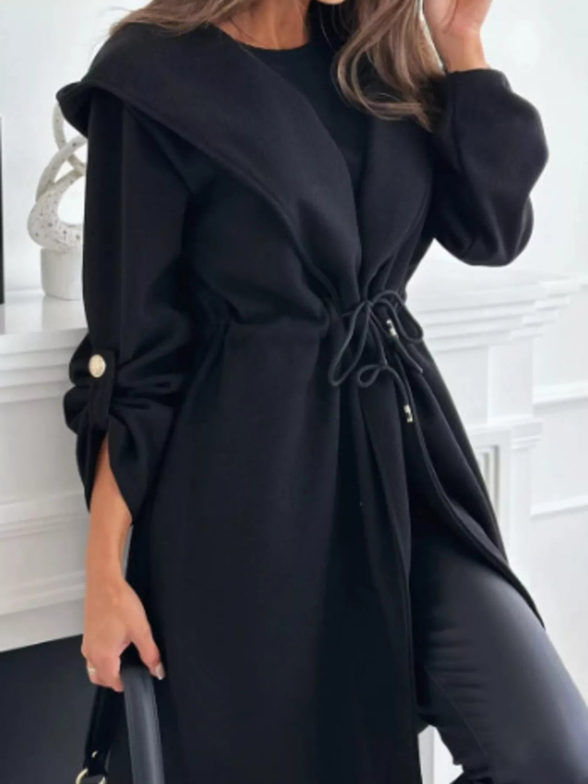Black hooded jacket with drawstring waist and front closure, draped long sleeves