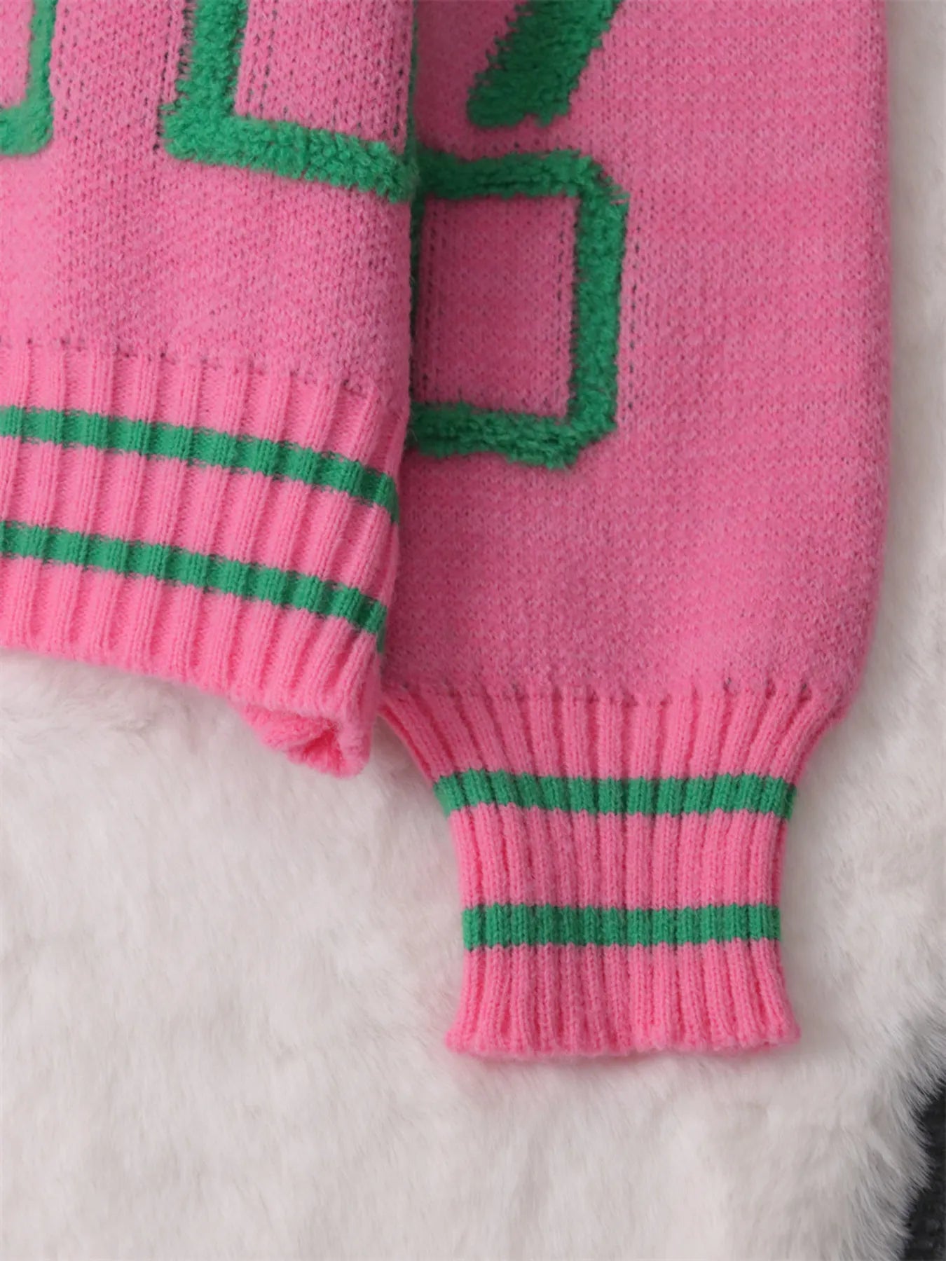 Pink round-neck long-sleeve sweater with green trim at hem and cuffs