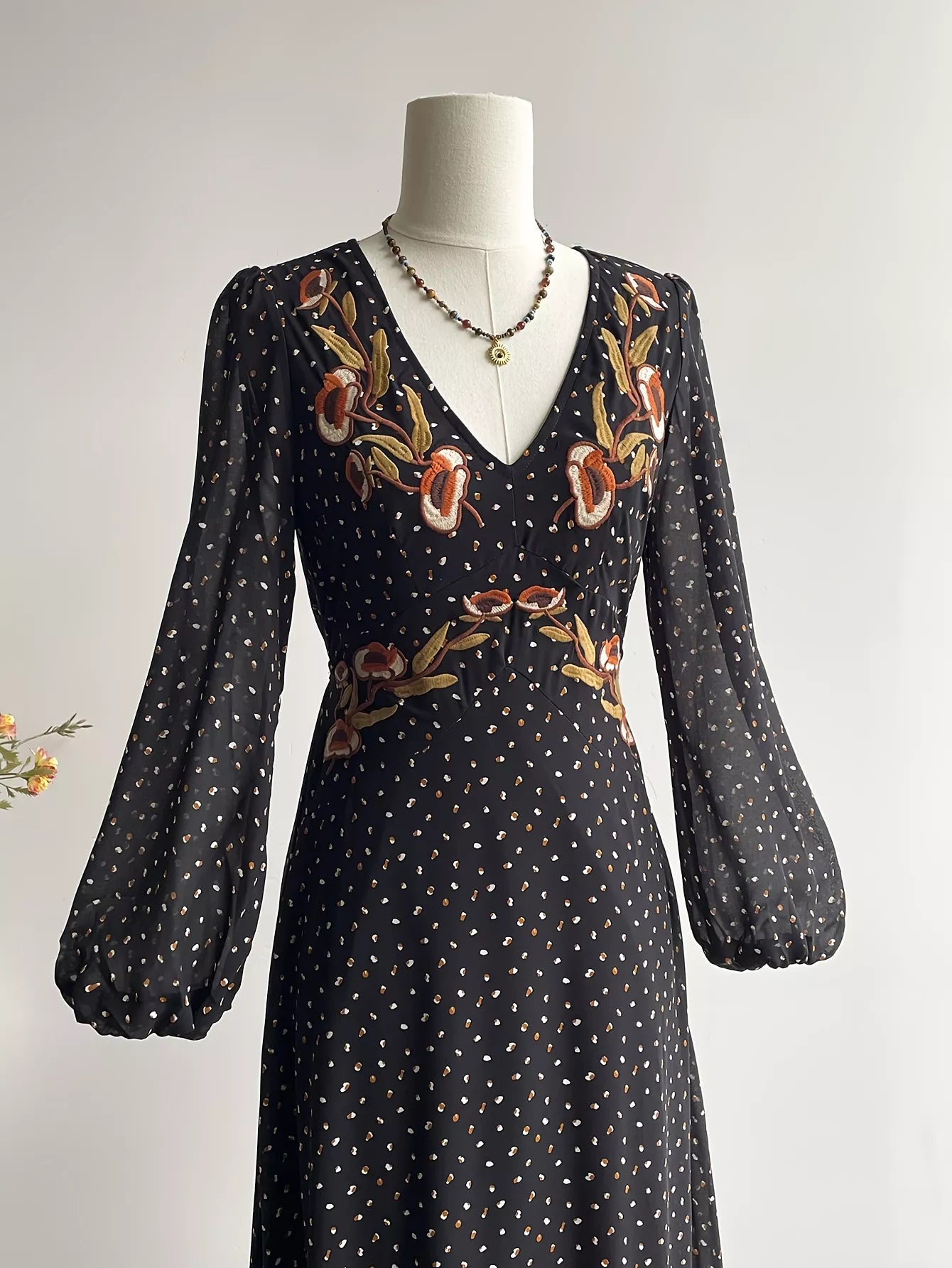 Black V-neck maxi dress with puff sleeves and colorful floral embroidery at bodice