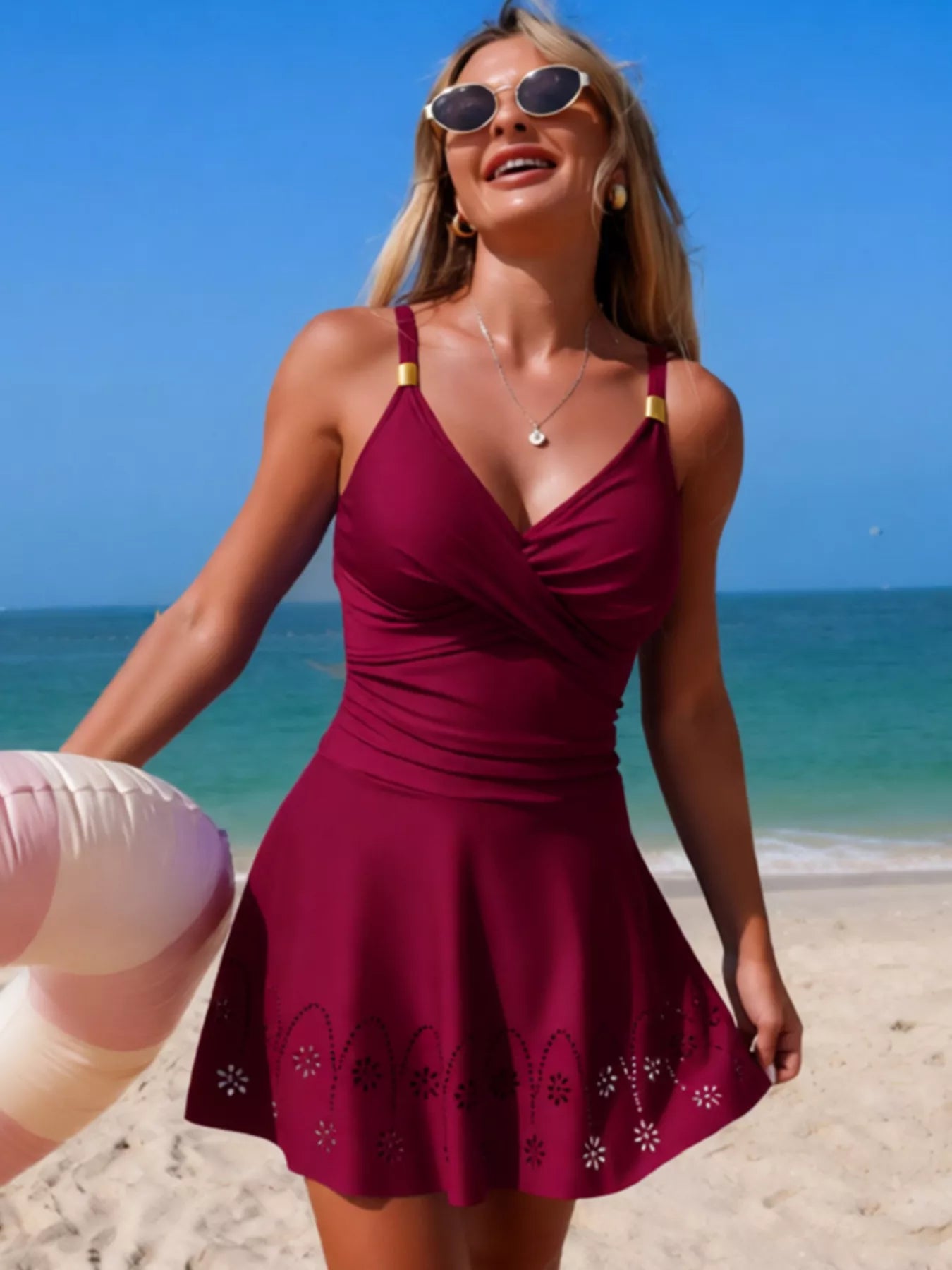 Crossover Ruched One-Piece Swim Dress in burgundy with gold strap hardware on model at the beach