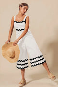 Wide-leg jumpsuit in ivory with scalloped ric rac trim and black wave bands.