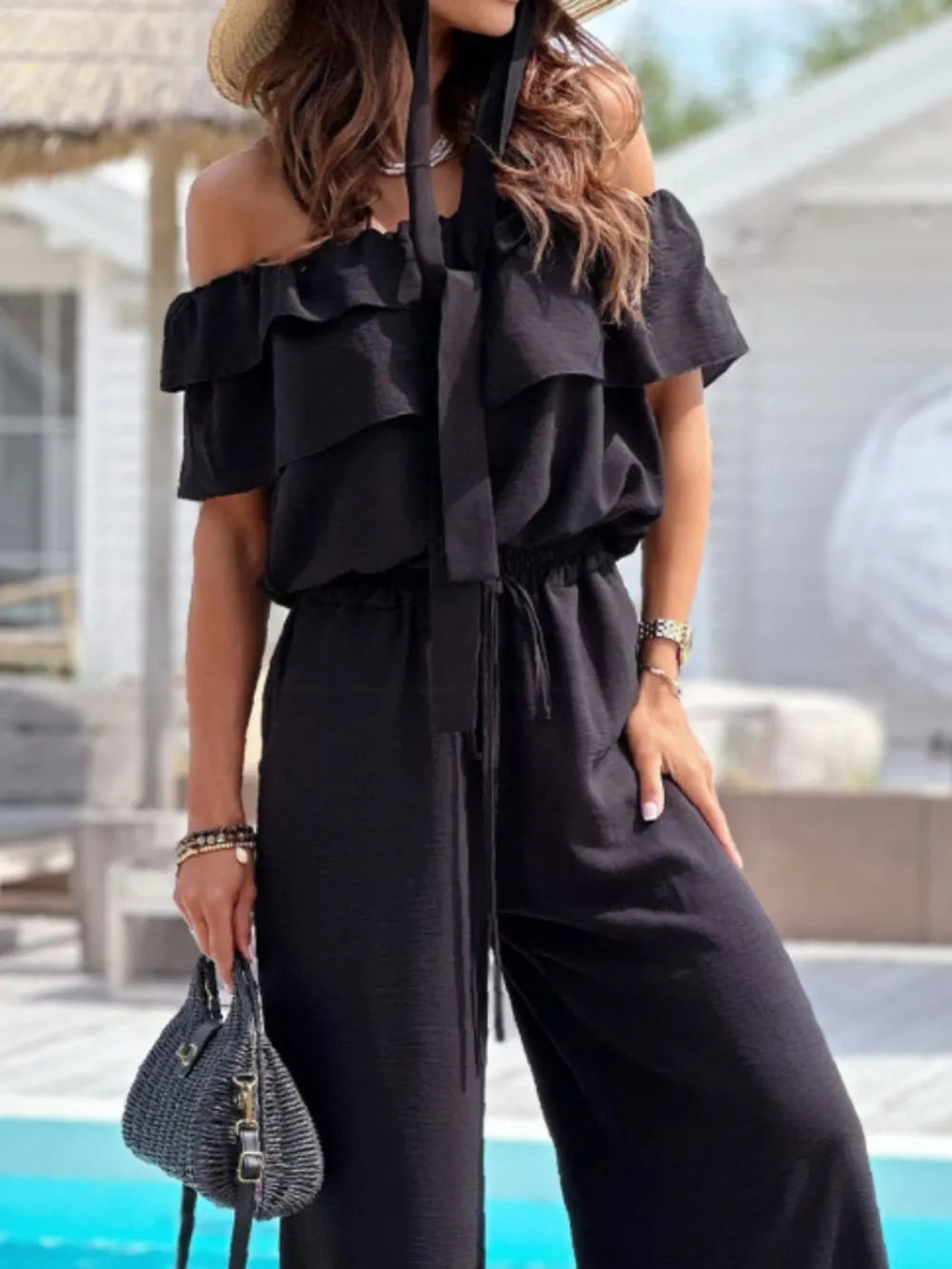 Black off-shoulder ruffled jumpsuit with layered shoulder ruffles and tie waist
