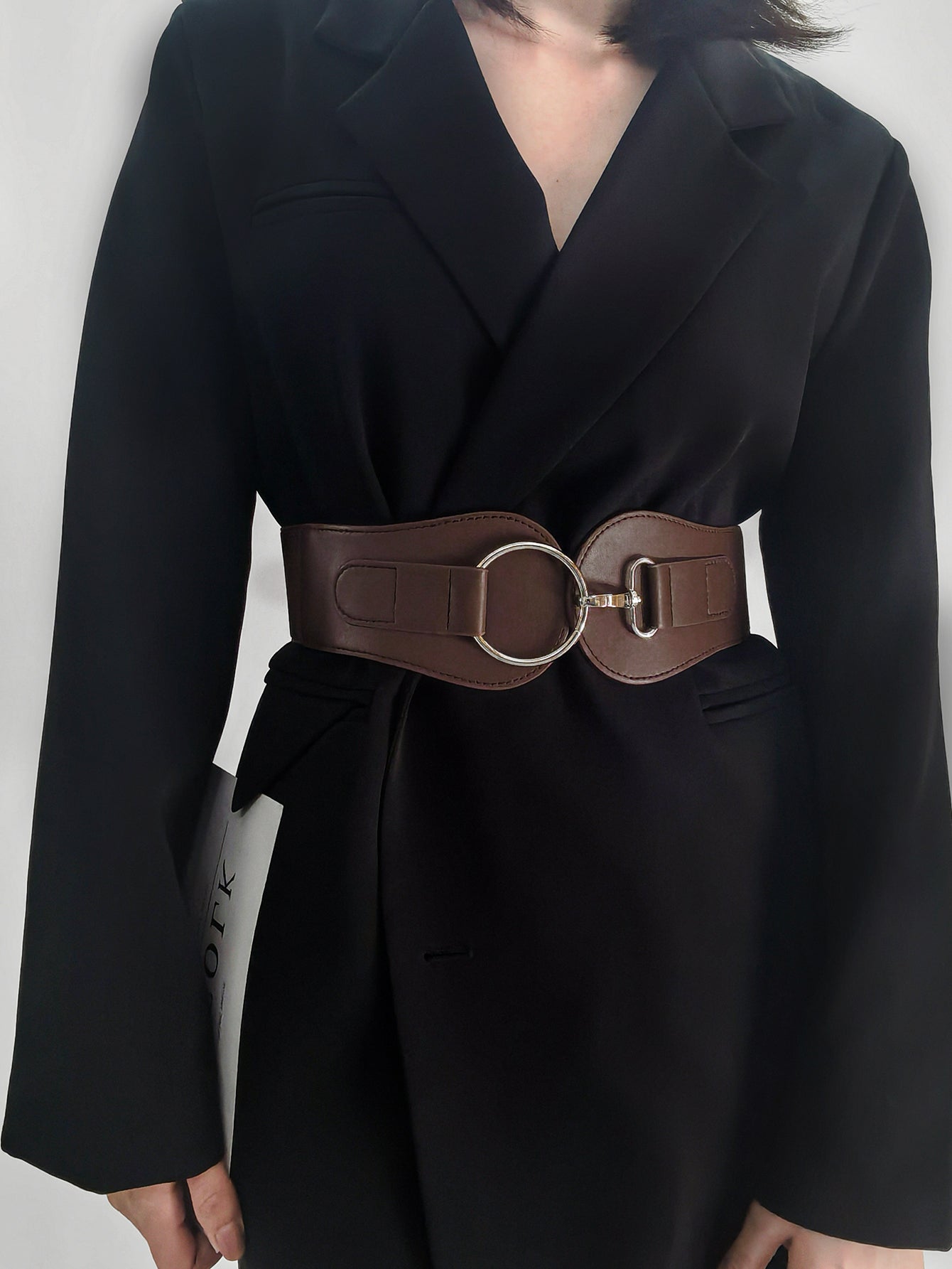 Wide elastic vegan leather belt in caramel brown with oval metal buckle and rings