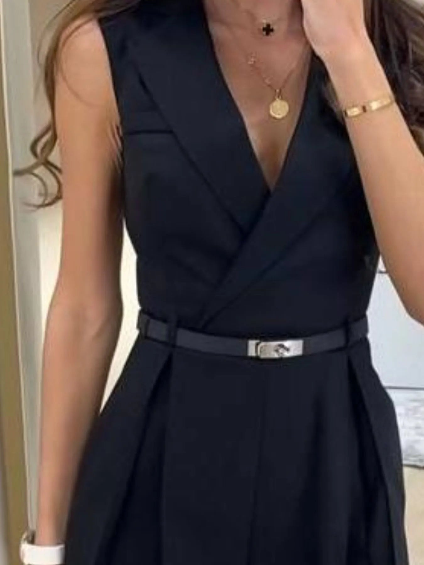 Navy sleeveless surplice romper close-up: V-neck, fitted belt and pleated waist
