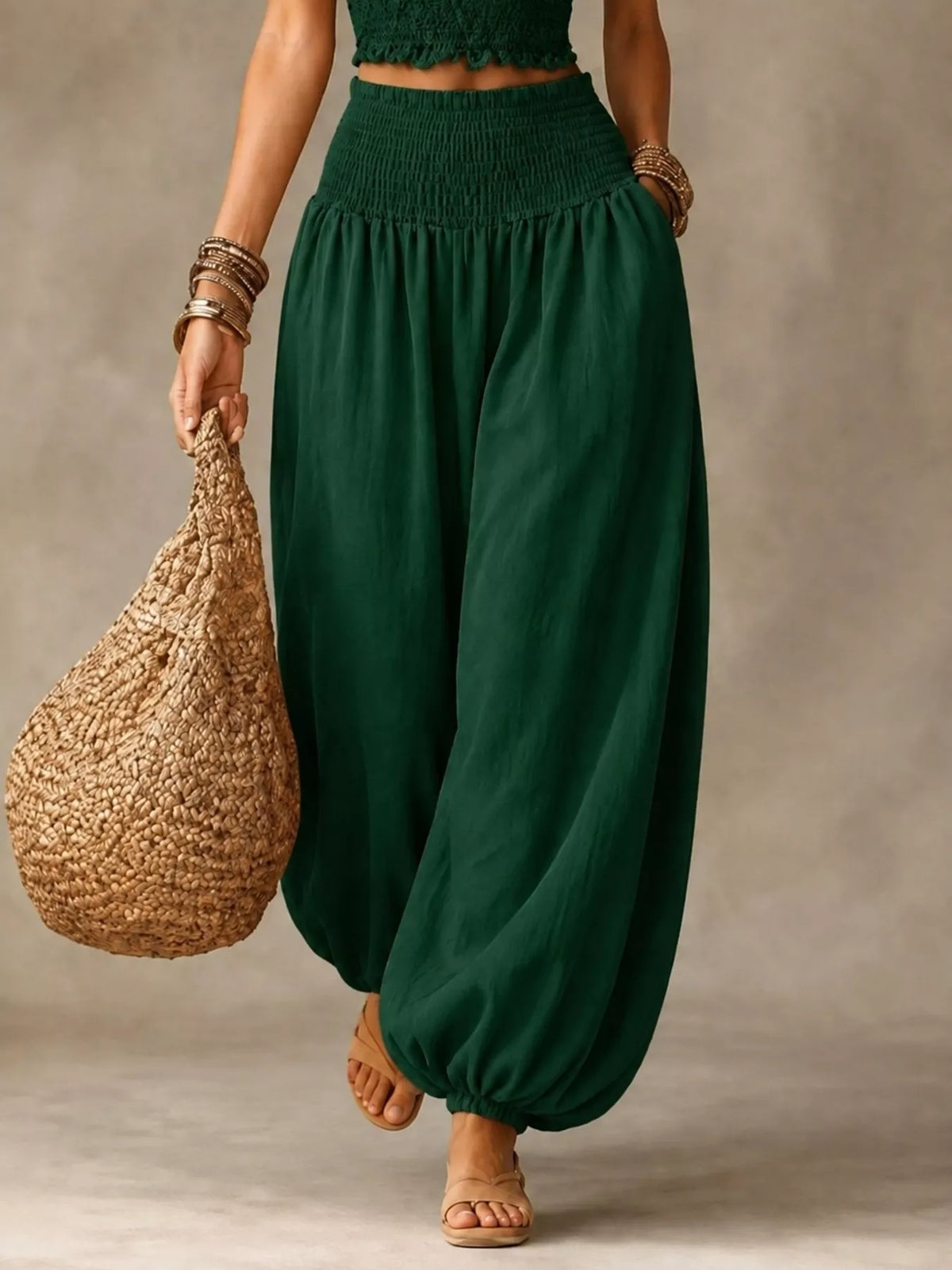 Green elastic-waist smocked harem pants with loose drape and ankle cuff gathers