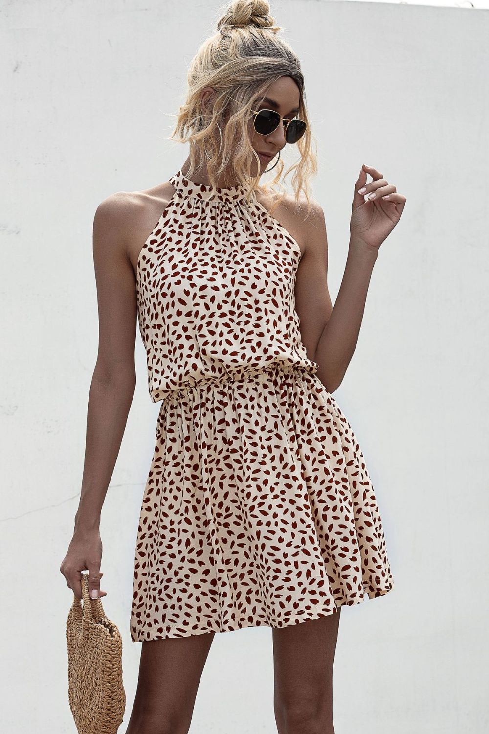 Tan printed halter mini dress with sleeveless Grecian neckline and tie waist
