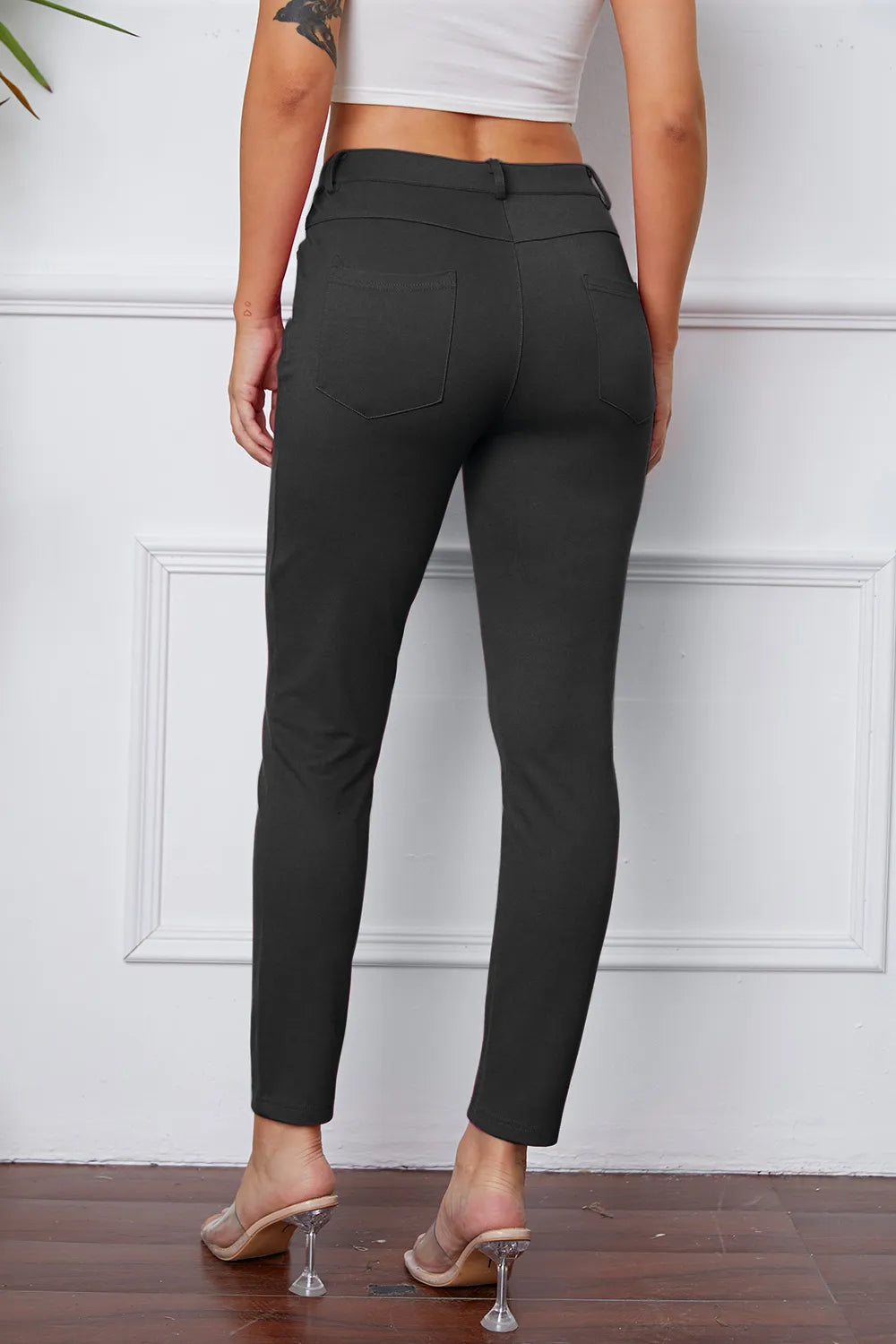 Black slim ankle pants with belt loops and front button; minimal seam detailing