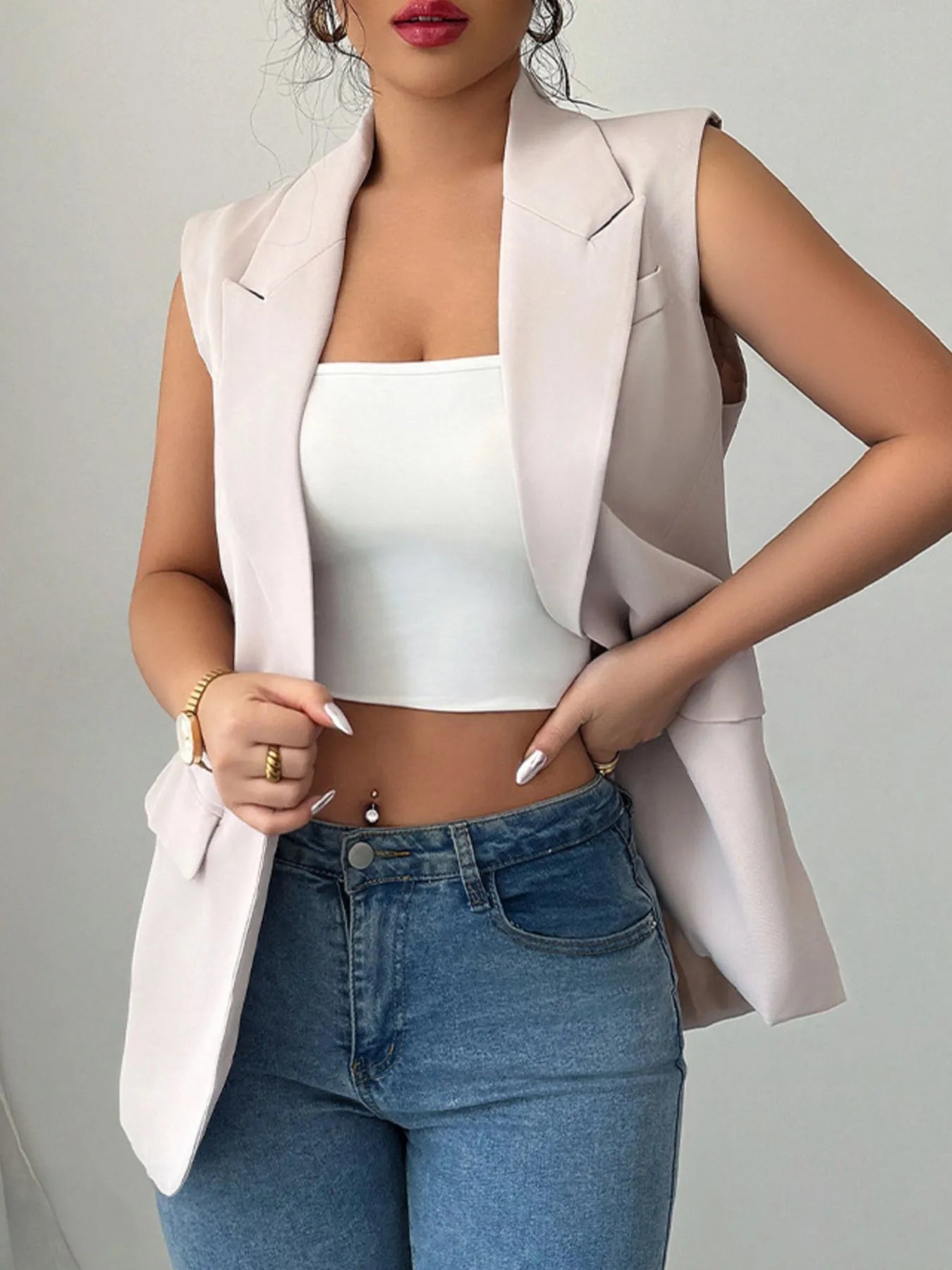 Eggshell sleeveless blazer with one button, open front, and flap pockets