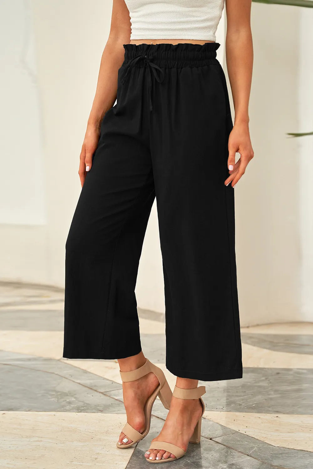 Black wide-leg pants with drawstring paperbag-style waist, loose fit through legs