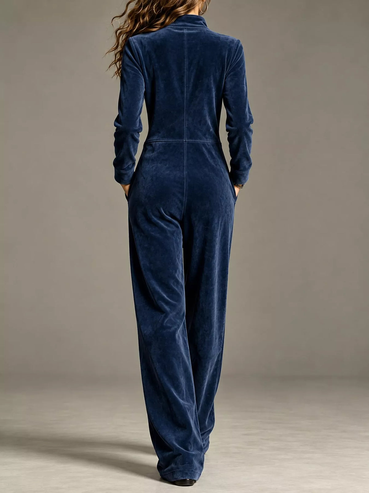 Dark blue velour zip-up jumpsuit with pockets and long sleeves, full-length back view
