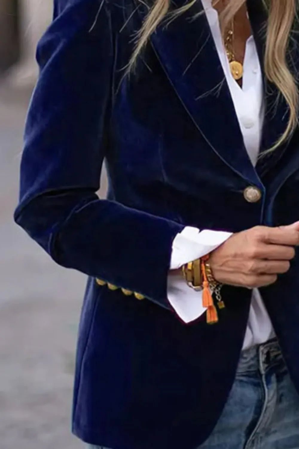 Close-up of dark navy one-button lapel blazer with long sleeves and front button.